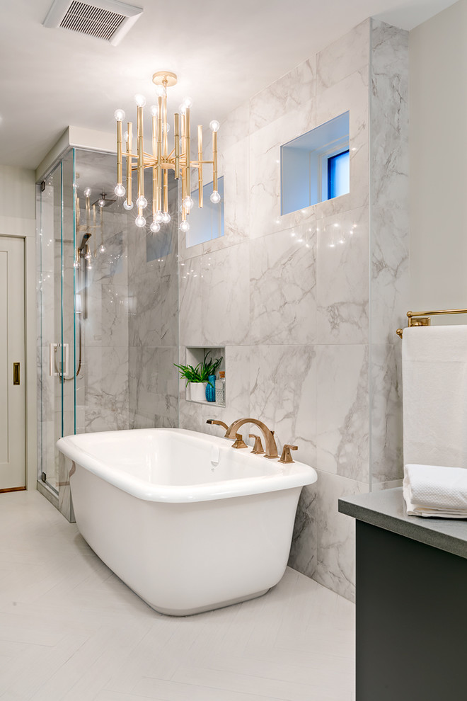 Cette image montre une grande salle de bain principale traditionnelle avec des portes de placard grises, une baignoire indépendante, une douche d'angle, un carrelage gris, un carrelage de pierre, un mur gris, un plan de toilette en quartz et un sol en carrelage de céramique.