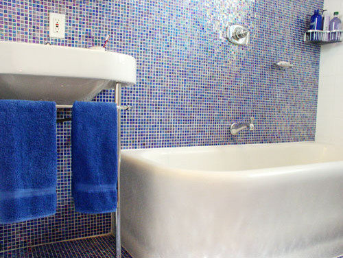 Idee per una piccola stanza da bagno padronale tradizionale con lavabo a consolle, vasca ad angolo, vasca/doccia, WC monopezzo, piastrelle blu, piastrelle di vetro, pareti blu e pavimento con piastrelle a mosaico