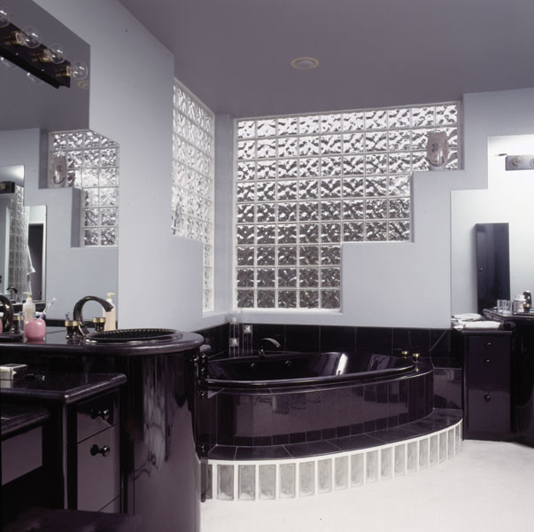 Exempel på ett mellanstort modernt en-suite badrum, med släta luckor, svarta skåp, ett hörnbadkar, svart kakel, grå väggar, ett nedsänkt handfat och bänkskiva i akrylsten