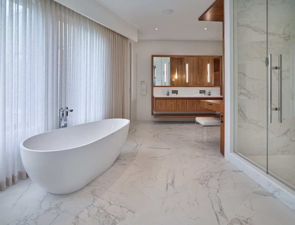 Réalisation d'une très grande salle de bain principale design en bois brun avec un lavabo encastré, un placard à porte plane, un plan de toilette en quartz, une baignoire indépendante, une douche double, un carrelage blanc, un carrelage de pierre, un mur blanc et un sol en carrelage de céramique.