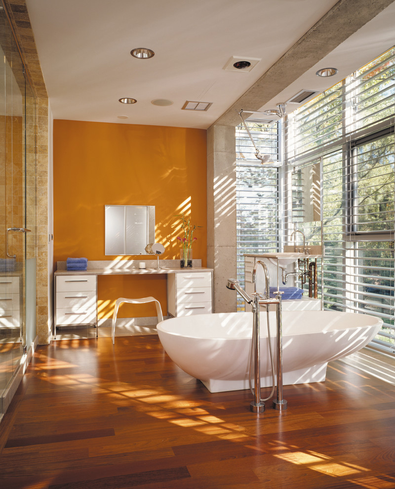 Freestanding bathtub - industrial master medium tone wood floor and brown floor freestanding bathtub idea in Chicago with orange walls and white cabinets