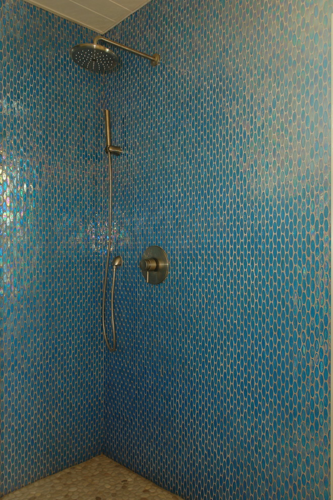 Large modern ensuite bathroom in Other with a corner shower, blue tiles, glass tiles, blue walls and pebble tile flooring.