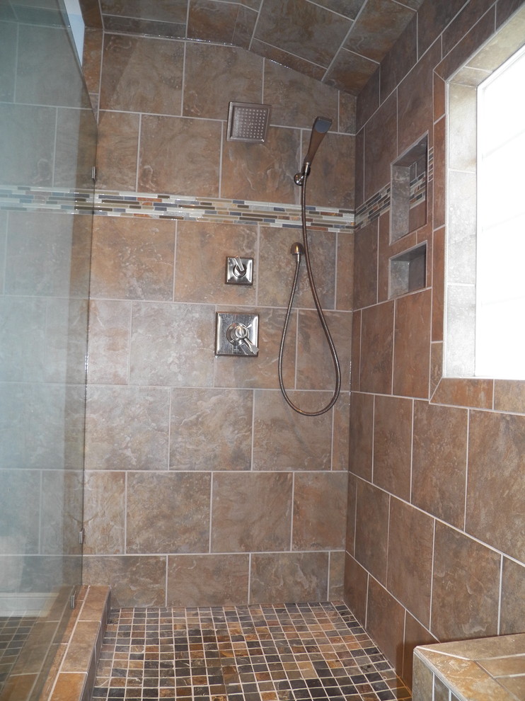 Elegant brown tile and stone tile alcove shower photo in Richmond with a hinged shower door