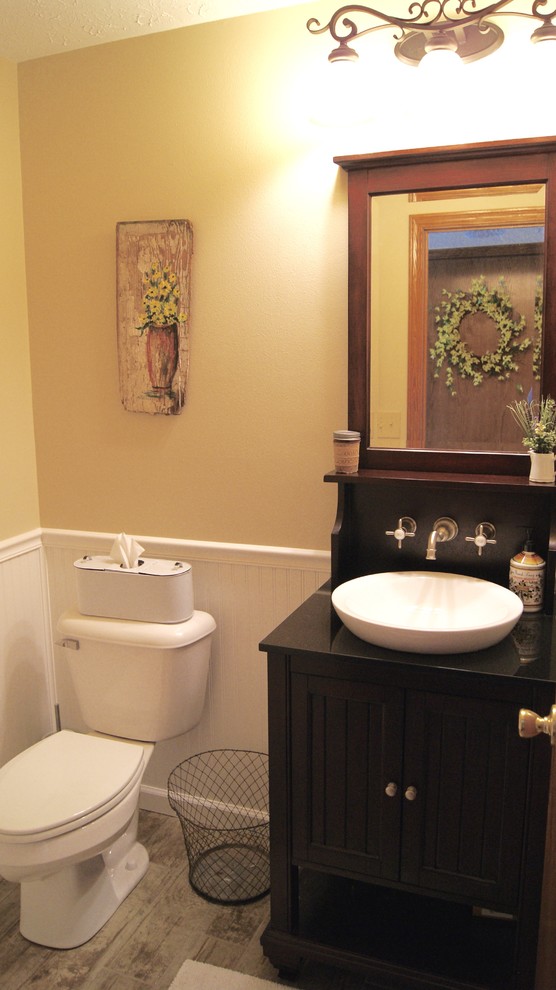 Inredning av ett lantligt litet badrum med dusch, med luckor med profilerade fronter, skåp i mörkt trä, en toalettstol med separat cisternkåpa, klinkergolv i porslin, ett fristående handfat och träbänkskiva
