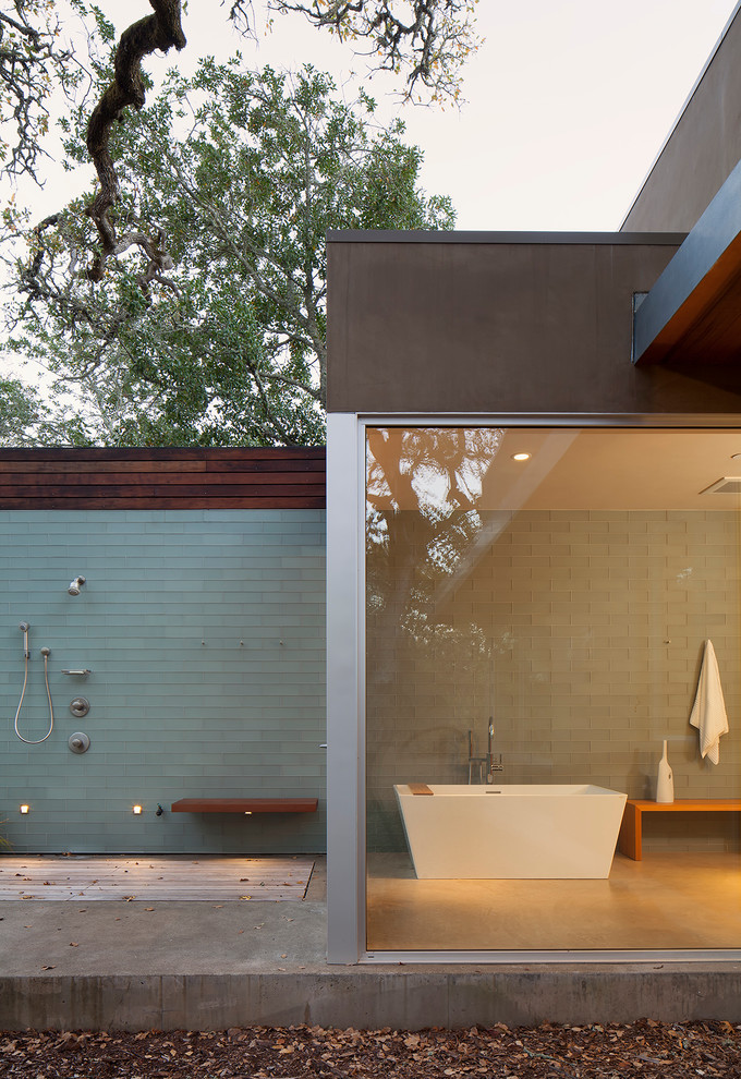Inredning av ett modernt badrum, med ett fristående badkar, en öppen dusch, blå kakel och glaskakel