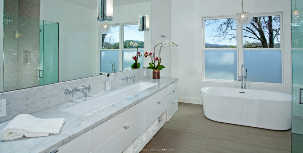 Идея дизайна: главная ванная комната среднего размера в современном стиле с плоскими фасадами, белыми фасадами, отдельно стоящей ванной, душем без бортиков, унитазом-моноблоком, белой плиткой, белыми стенами, паркетным полом среднего тона, врезной раковиной, мраморной столешницей, коричневым полом и шторкой для ванной