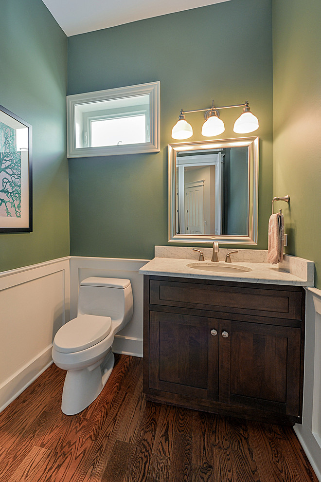 Inspiration pour une petite salle de bain traditionnelle en bois brun avec un placard à porte shaker, WC à poser, un mur vert, un sol en bois brun, un lavabo encastré et un plan de toilette en quartz.