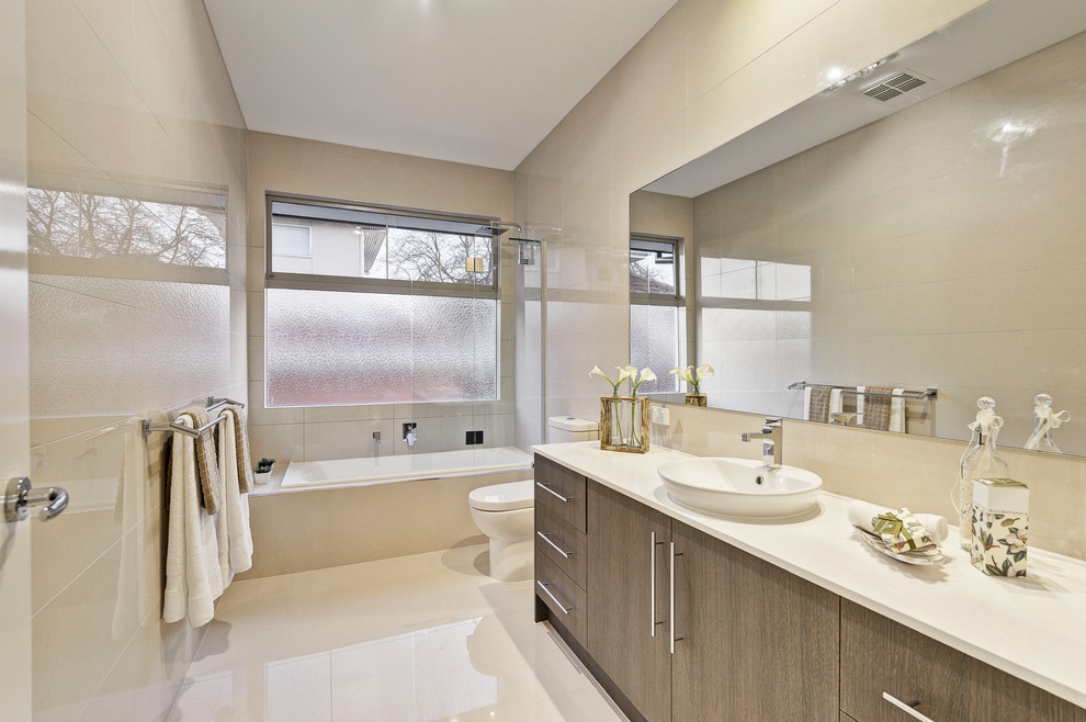 Bild på ett mellanstort funkis vit vitt badrum, med ett platsbyggt badkar, beige kakel, ett fristående handfat, beiget golv, släta luckor, bänkskiva i kvarts, skåp i mörkt trä och en dusch/badkar-kombination