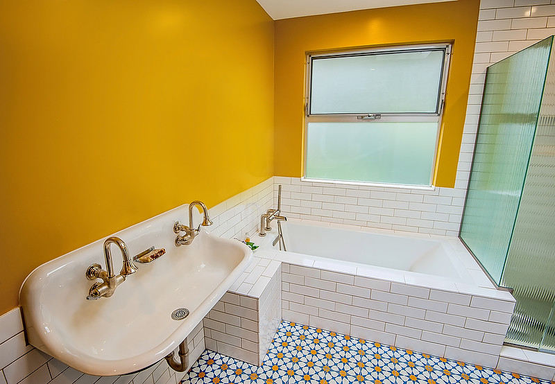 Стильный дизайн: ванная комната среднего размера в стиле ретро с открытыми фасадами, полновстраиваемой ванной, угловым душем, раздельным унитазом, белой плиткой, каменной плиткой, желтыми стенами, полом из цементной плитки, душевой кабиной, раковиной с несколькими смесителями, столешницей из искусственного камня, синим полом и душем с распашными дверями - последний тренд