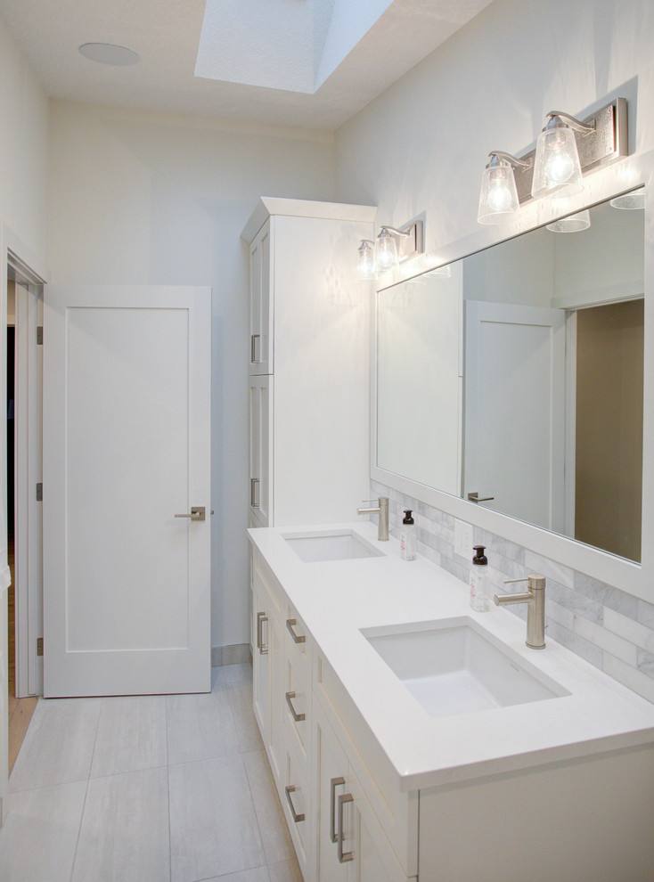 Inredning av ett modernt mellanstort vit vitt en-suite badrum, med skåp i shakerstil, vita skåp, ett platsbyggt badkar, en dusch/badkar-kombination, en toalettstol med hel cisternkåpa, vit kakel, keramikplattor, vita väggar, klinkergolv i keramik, ett undermonterad handfat, bänkskiva i kvarts, grått golv och dusch med duschdraperi