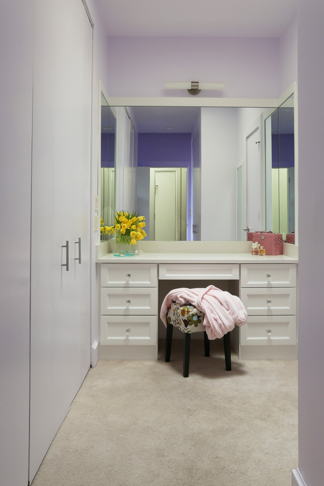 This is an example of a medium sized contemporary dressing room for women in Chicago with recessed-panel cabinets, white cabinets, beige floors and carpet.