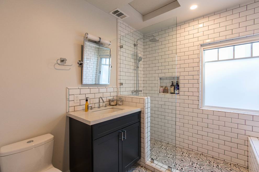 This is an example of a medium sized classic shower room bathroom in Los Angeles with shaker cabinets, black cabinets, an alcove shower, a one-piece toilet, white tiles, metro tiles, grey walls, cement flooring, a submerged sink, engineered stone worktops, multi-coloured floors, an open shower and white worktops.