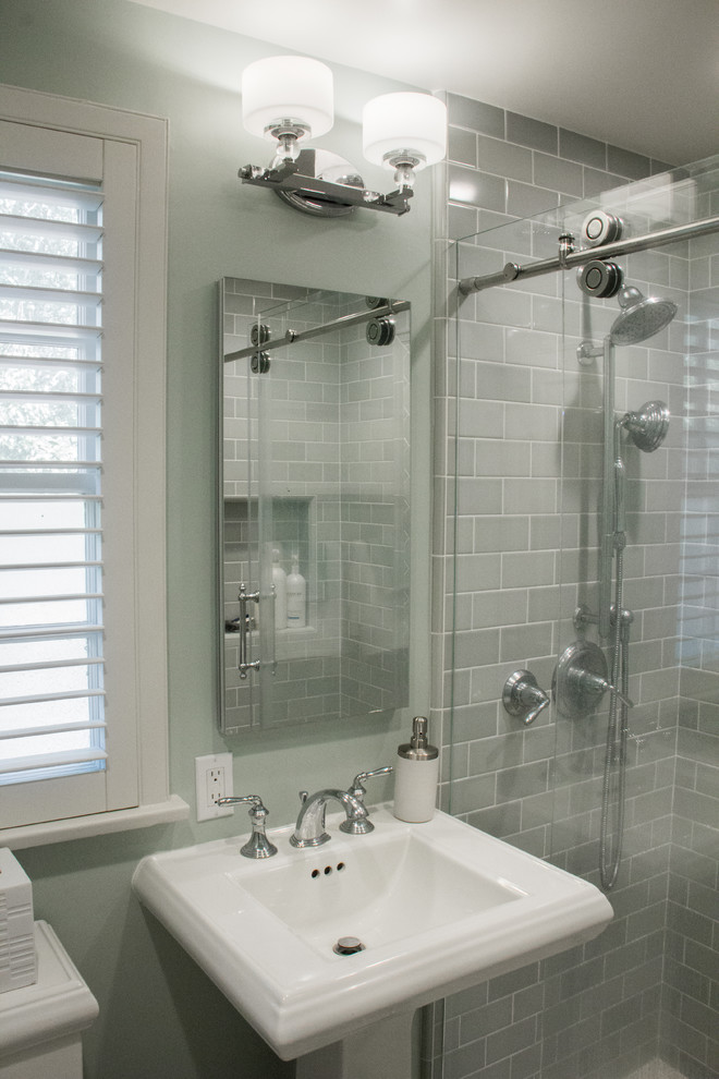Inredning av ett klassiskt litet badrum med dusch, med en dusch i en alkov, en toalettstol med separat cisternkåpa, grön kakel, tunnelbanekakel, gröna väggar, cementgolv, ett piedestal handfat, vitt golv och dusch med skjutdörr