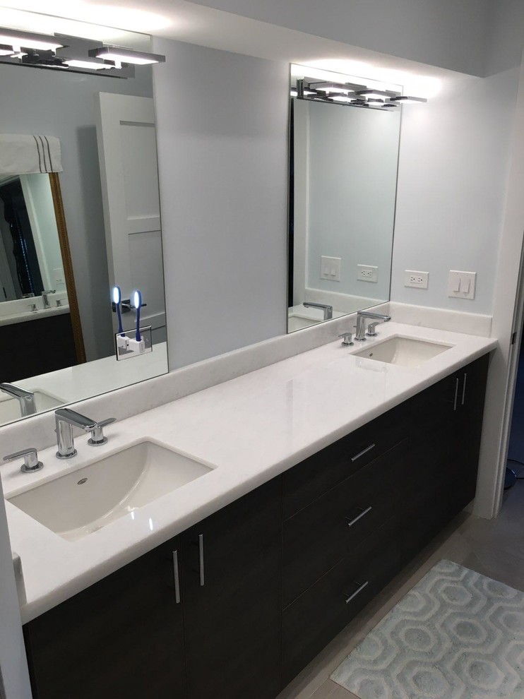 Inspiration for a mid-sized contemporary master white tile and porcelain tile porcelain tile and beige floor bathroom remodel in Miami with flat-panel cabinets, dark wood cabinets, a one-piece toilet, gray walls, an undermount sink, quartz countertops and a hinged shower door