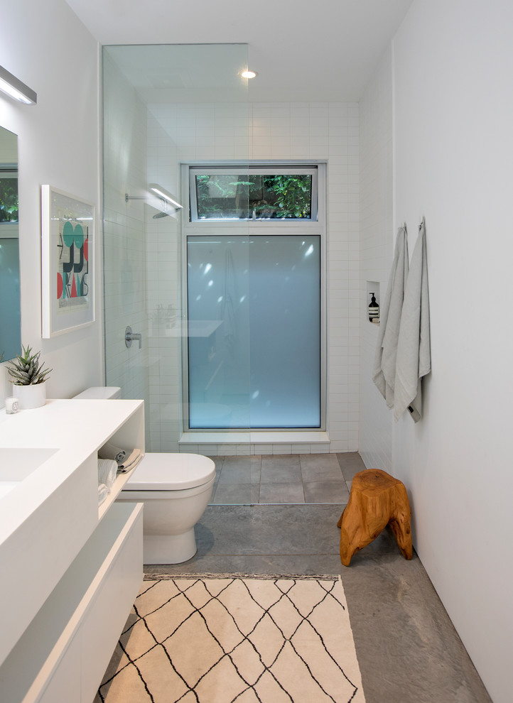 Свежая идея для дизайна: ванная комната среднего размера в стиле модернизм с плоскими фасадами, белыми фасадами, душем без бортиков, унитазом-моноблоком, белыми стенами, бетонным полом, душевой кабиной, подвесной раковиной, столешницей из ламината, серым полом, открытым душем и белой столешницей - отличное фото интерьера