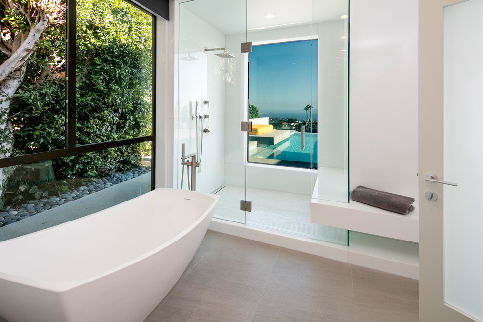 ロサンゼルスにある中くらいなコンテンポラリースタイルのおしゃれなマスターバスルーム (置き型浴槽、アルコーブ型シャワー、白いタイル、石スラブタイル、白い壁、磁器タイルの床、グレーの床、開き戸のシャワー) の写真