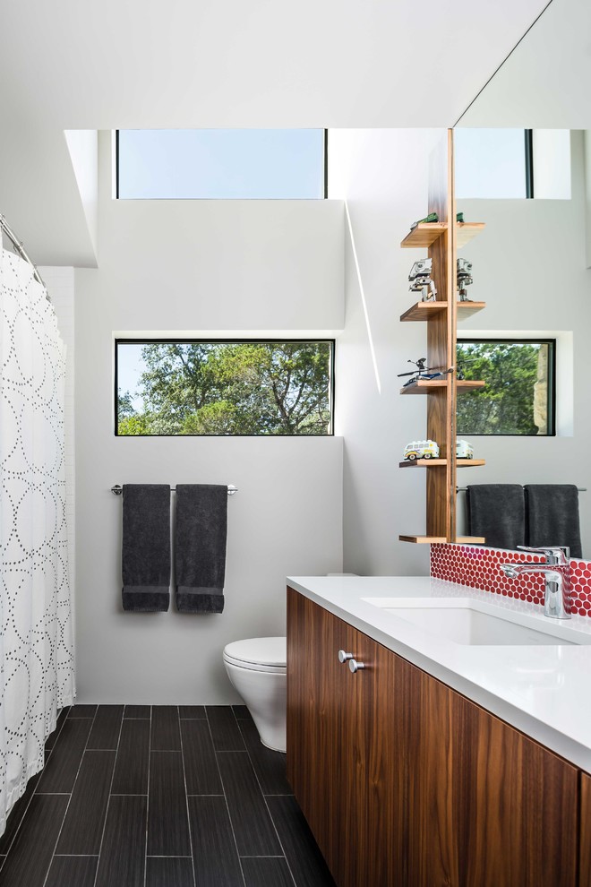 Foto på ett 50 tals badrum, med ett undermonterad handfat, släta luckor, skåp i mellenmörkt trä, vita väggar, dusch med duschdraperi och en dusch i en alkov