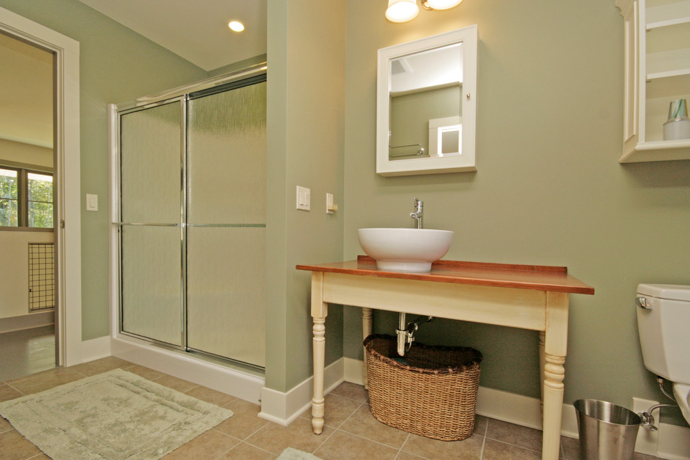 Photo of a contemporary bathroom in Grand Rapids with freestanding cabinets, a two-piece toilet, beige walls, slate flooring, a vessel sink and wooden worktops.