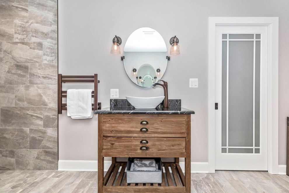 Cette photo montre une salle de bain principale moderne en bois brun de taille moyenne avec un placard en trompe-l'oeil, une douche ouverte, un mur gris, une vasque, un plan de toilette en granite, un sol beige, aucune cabine et un plan de toilette noir.