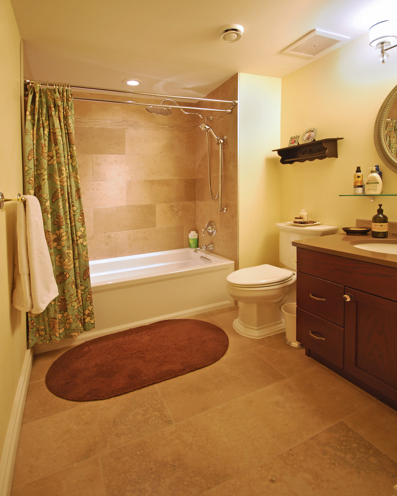 Photo of a medium sized traditional bathroom in Edmonton with a submerged sink, shaker cabinets, dark wood cabinets, granite worktops, an alcove bath, a shower/bath combination, a two-piece toilet, beige tiles, ceramic tiles, yellow walls and ceramic flooring.