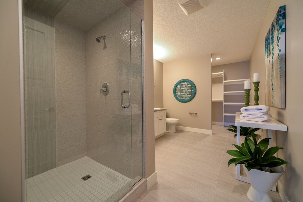 Bathroom - large contemporary master beige tile and ceramic tile vinyl floor and beige floor bathroom idea in Calgary with recessed-panel cabinets, white cabinets, a two-piece toilet, beige walls, a drop-in sink, solid surface countertops and a hinged shower door