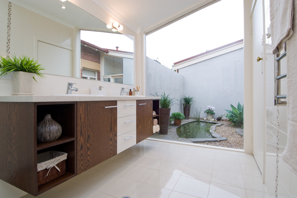 Mittelgroßes Modernes Duschbad mit Einbauwaschbecken, dunklen Holzschränken, Eckdusche, Wandtoilette mit Spülkasten, beigen Fliesen und beiger Wandfarbe in Sonstige