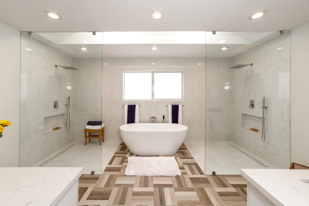Свежая идея для дизайна: большая главная ванная комната в стиле модернизм с плоскими фасадами, белыми фасадами, угловой ванной, душем без бортиков, раздельным унитазом, серой плиткой, мраморной плиткой, белыми стенами, полом из керамогранита, врезной раковиной, столешницей из искусственного кварца, разноцветным полом, открытым душем и белой столешницей - отличное фото интерьера