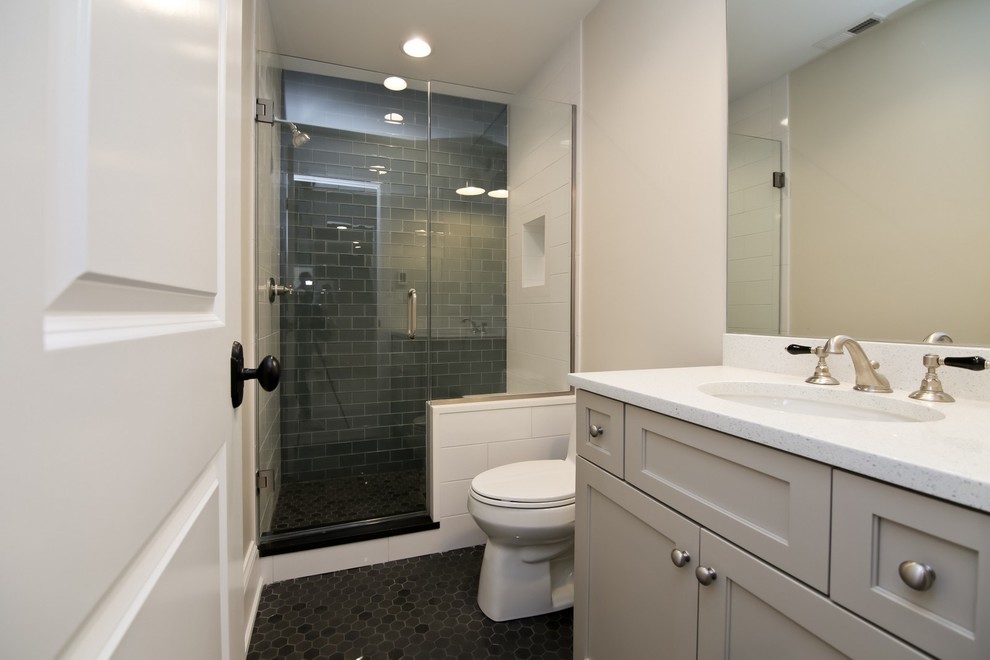 На фото: главная ванная комната среднего размера в стиле неоклассика (современная классика) с фасадами с утопленной филенкой, серыми фасадами, угловым душем, унитазом-моноблоком, серыми стенами, врезной раковиной, черной плиткой, стеклянной плиткой, полом из мозаичной плитки, столешницей из искусственного кварца, черным полом, душем с распашными дверями и белой столешницей с