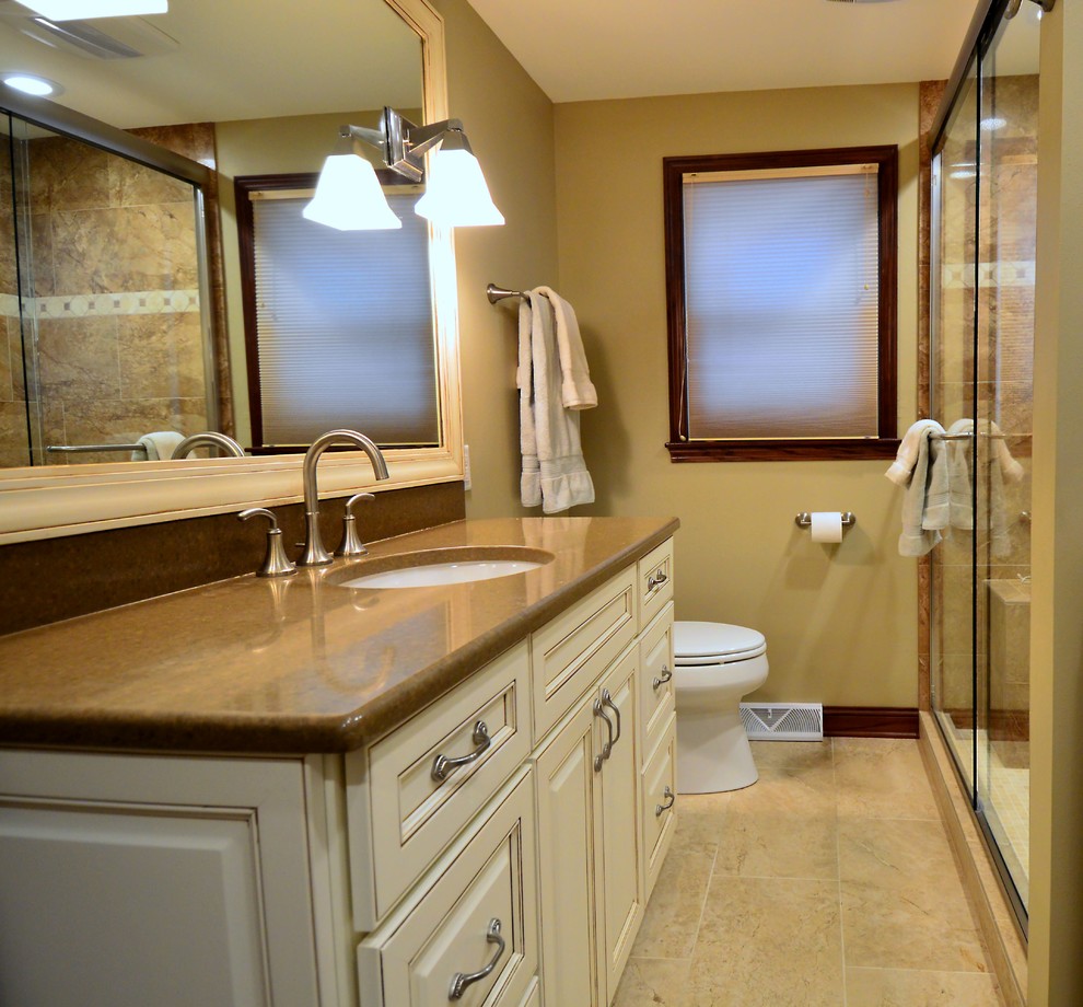 Inredning av ett klassiskt litet badrum med dusch, med luckor med upphöjd panel, beige skåp, en dusch i en alkov, en toalettstol med separat cisternkåpa, brun kakel, stenkakel, beige väggar, klinkergolv i keramik, ett nedsänkt handfat, laminatbänkskiva, beiget golv och dusch med gångjärnsdörr