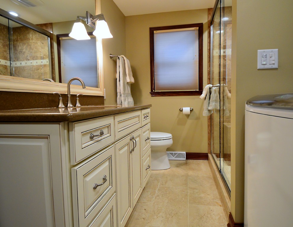 Cette image montre une petite salle de bain traditionnelle avec un placard avec porte à panneau surélevé, WC séparés, des portes de placard beiges, un carrelage marron, un carrelage de pierre, un mur beige, un sol en carrelage de céramique, un lavabo posé, un plan de toilette en stratifié, un sol beige et une cabine de douche à porte battante.