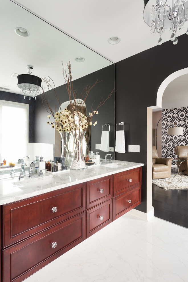 Cette image montre une salle de bain principale traditionnelle en bois brun de taille moyenne avec un mur noir, un lavabo encastré, un carrelage noir et blanc, des carreaux de porcelaine, un plan de toilette en marbre, une baignoire posée, WC à poser, un sol en marbre et un placard avec porte à panneau encastré.