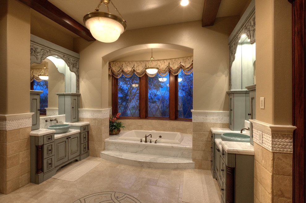 Diseño de cuarto de baño principal tradicional grande con lavabo sobreencimera, puertas de armario verdes, encimera de mármol, bañera encastrada, baldosas y/o azulejos beige, paredes beige y suelo de baldosas de cerámica