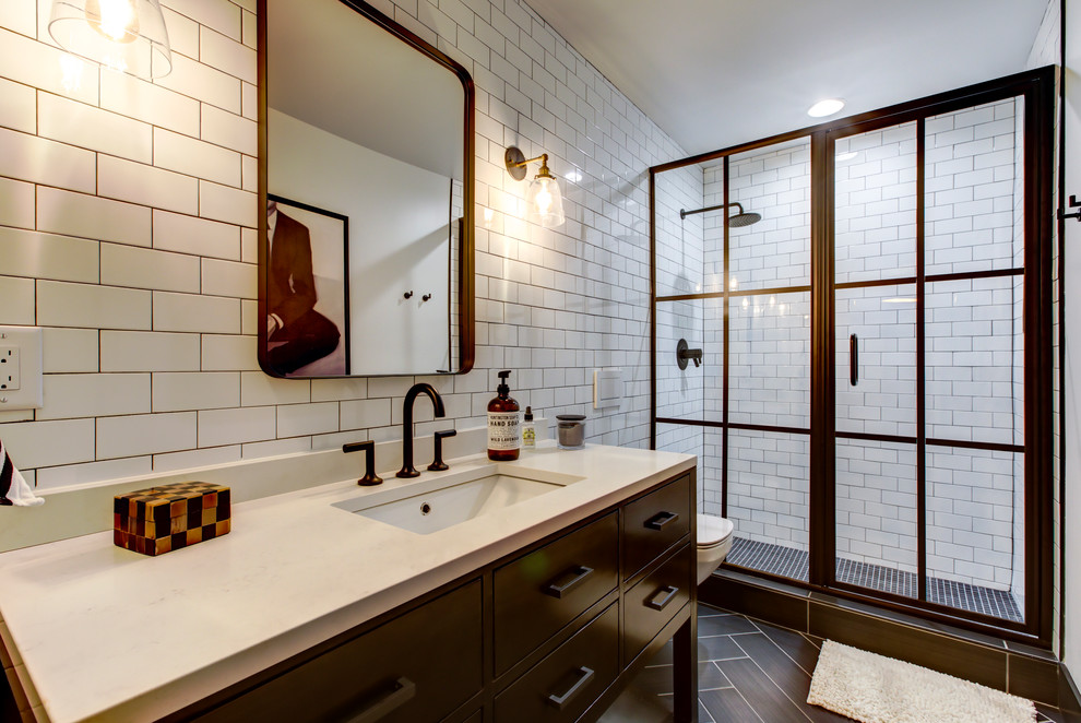 Mid-sized urban 3/4 white tile and subway tile porcelain tile and brown floor bathroom photo in Raleigh with black cabinets, a wall-mount toilet, white walls, an undermount sink, quartz countertops, white countertops and flat-panel cabinets