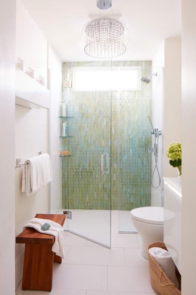 Idéer för att renovera ett litet funkis en-suite badrum, med en kantlös dusch, en toalettstol med separat cisternkåpa, glaskakel, vita väggar, klinkergolv i porslin, ett väggmonterat handfat, bänkskiva i glas, luckor med glaspanel, vita skåp, grön kakel, vitt golv och dusch med gångjärnsdörr