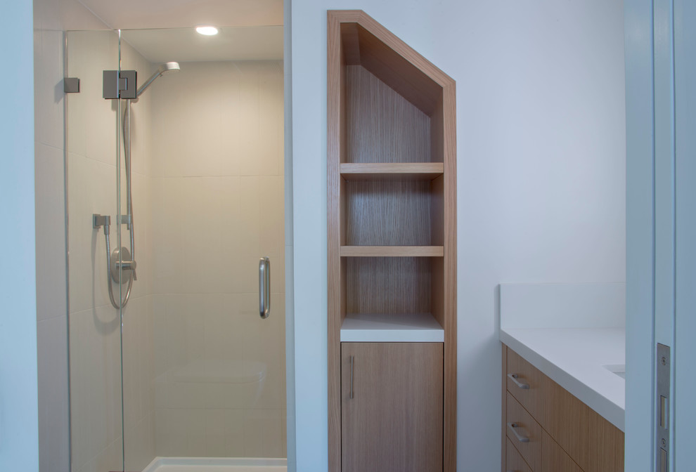 Modern inredning av ett mellanstort en-suite badrum, med släta luckor, skåp i ljust trä, en dusch i en alkov, vit kakel, keramikplattor, vita väggar, ett undermonterad handfat, bänkskiva i kvarts, en toalettstol med separat cisternkåpa och dusch med gångjärnsdörr