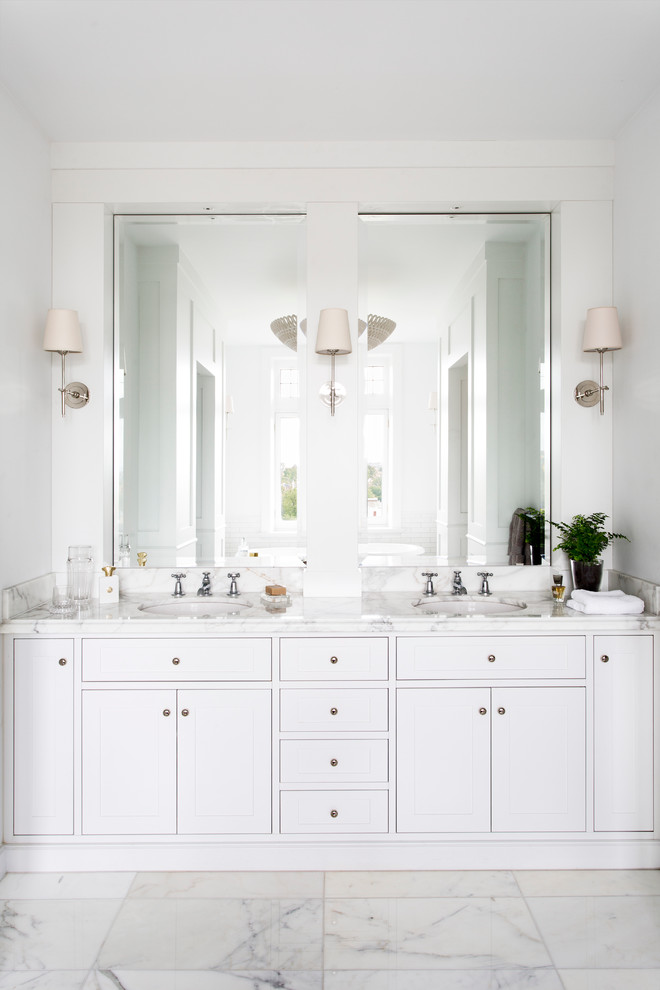 Foto de cuarto de baño principal tradicional con lavabo bajoencimera, puertas de armario blancas, encimera de mármol, baldosas y/o azulejos blancos, paredes blancas, suelo de mármol y encimeras blancas