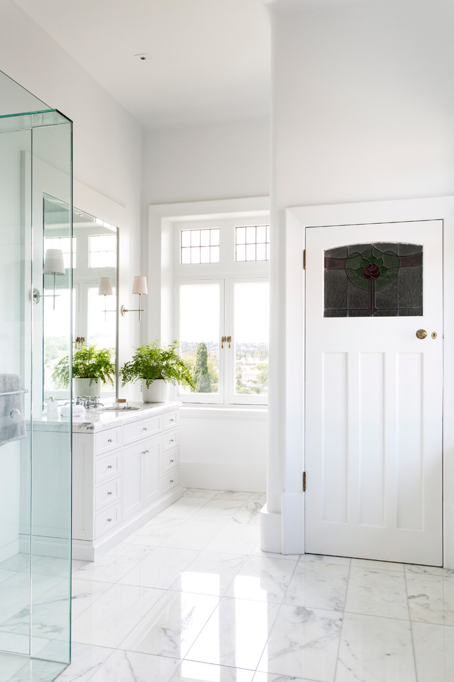 Идея дизайна: ванная комната в классическом стиле с врезной раковиной, фасадами в стиле шейкер, белыми фасадами, мраморной столешницей, угловым душем, белой плиткой, белыми стенами и мраморным полом