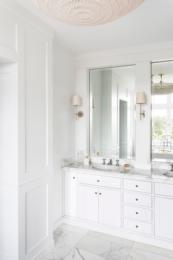 Large classic ensuite bathroom in Melbourne with a submerged sink, recessed-panel cabinets, white cabinets, marble worktops, a freestanding bath, an alcove shower, a one-piece toilet, white tiles, metro tiles, white walls and marble flooring.