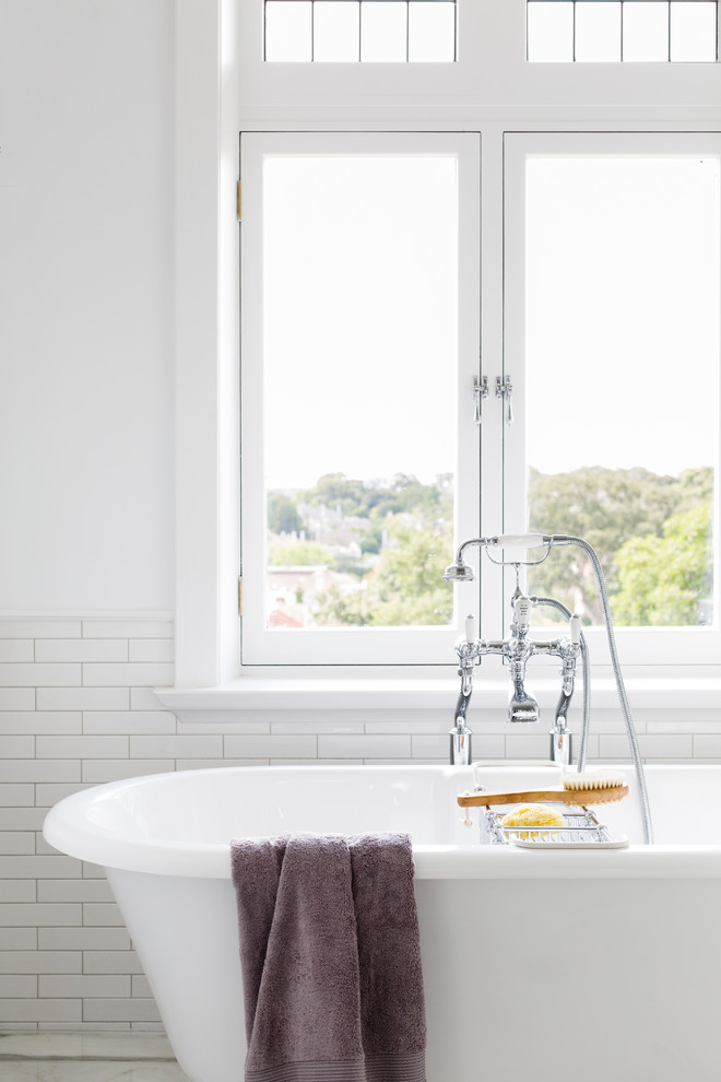 Photo of a large traditional ensuite bathroom in Melbourne with a submerged sink, recessed-panel cabinets, white cabinets, marble worktops, a freestanding bath, an alcove shower, a one-piece toilet, white tiles, metro tiles, white walls and marble flooring.