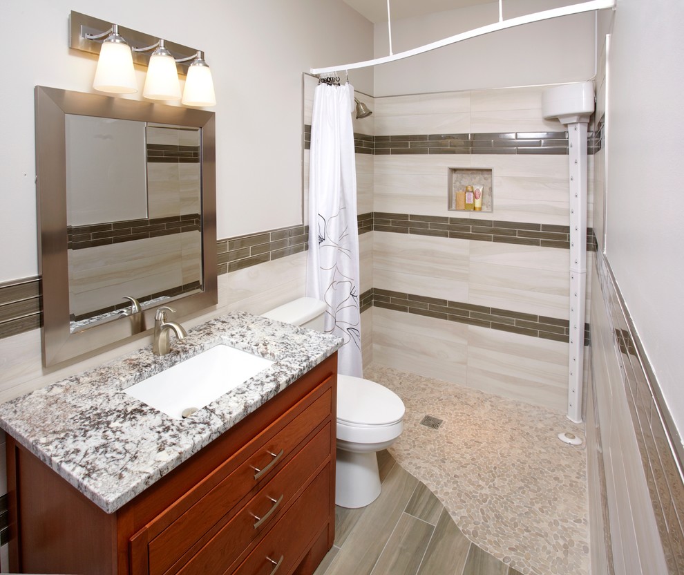 Example of a mid-sized minimalist 3/4 beige tile, brown tile and porcelain tile pebble tile floor and beige floor bathroom design in Denver with raised-panel cabinets, dark wood cabinets, a two-piece toilet, beige walls, an undermount sink and quartz countertops