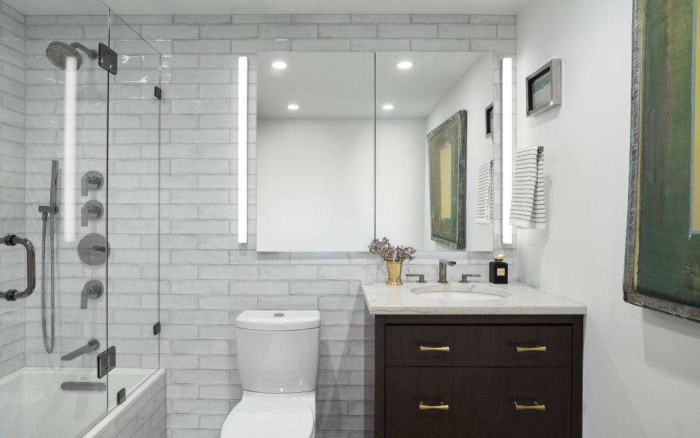 Design ideas for a medium sized contemporary ensuite bathroom in Chicago with flat-panel cabinets, dark wood cabinets, a shower/bath combination, a two-piece toilet, white tiles, ceramic tiles, white walls, marble flooring, a submerged sink, quartz worktops, grey floors, a hinged door and grey worktops.