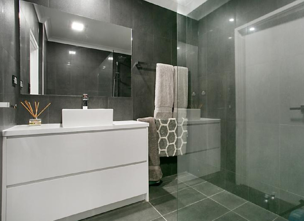 Design ideas for a small contemporary ensuite bathroom in Gold Coast - Tweed with flat-panel cabinets, white cabinets, a corner shower, grey tiles, ceramic tiles, ceramic flooring, a vessel sink, grey floors, an open shower, grey walls and engineered stone worktops.