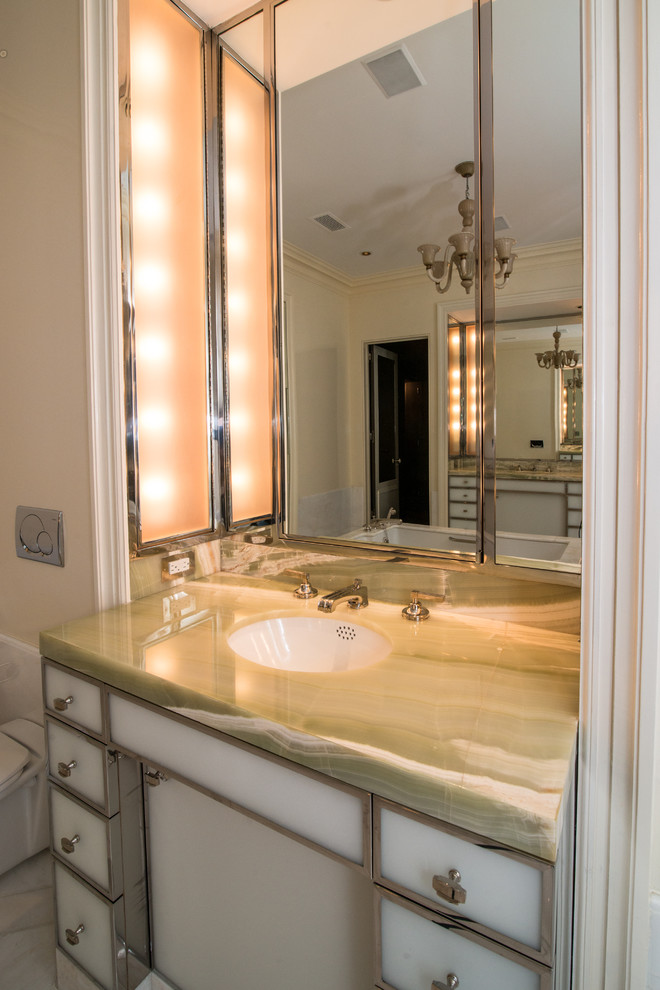 Modern inredning av ett stort en-suite badrum, med marmorgolv, bänkskiva i onyx, släta luckor, ett fristående badkar, en bidé, beige väggar och ett undermonterad handfat