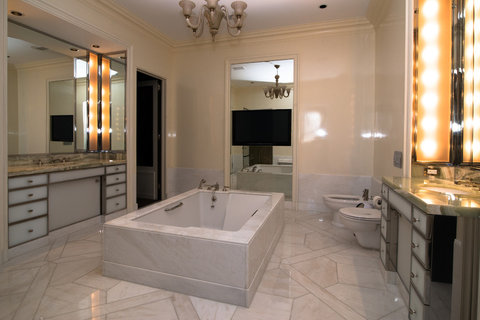 Diseño de cuarto de baño principal actual grande con suelo de mármol, encimera de ónix, armarios con paneles lisos, bañera exenta, bidé, paredes beige y lavabo bajoencimera