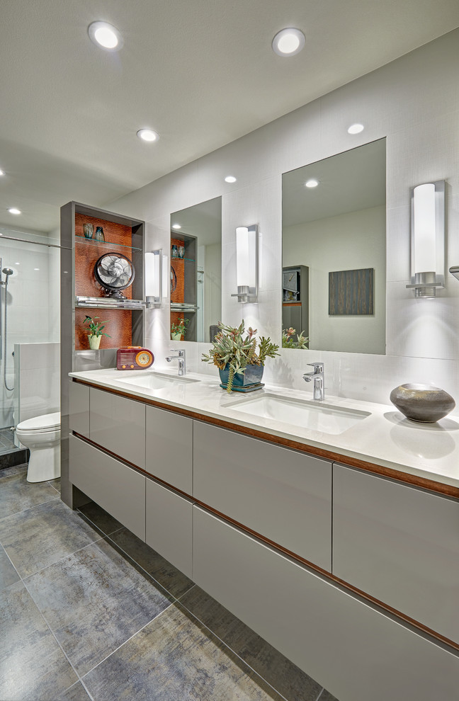 Inspiration for a large modern family bathroom in Sacramento with flat-panel cabinets, grey cabinets, a walk-in shower, a one-piece toilet, white tiles, porcelain tiles, white walls, porcelain flooring, a submerged sink, engineered stone worktops, grey floors and a hinged door.