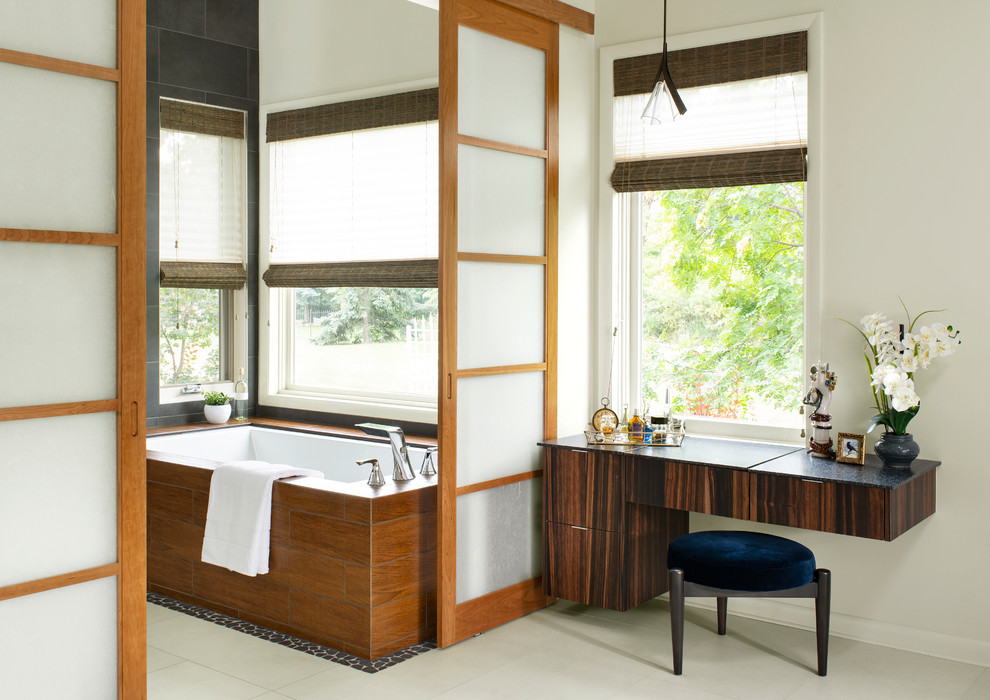 Immagine di una stanza da bagno contemporanea con ante lisce, ante in legno bruno, vasca sottopiano, pareti beige, pavimento beige e top nero