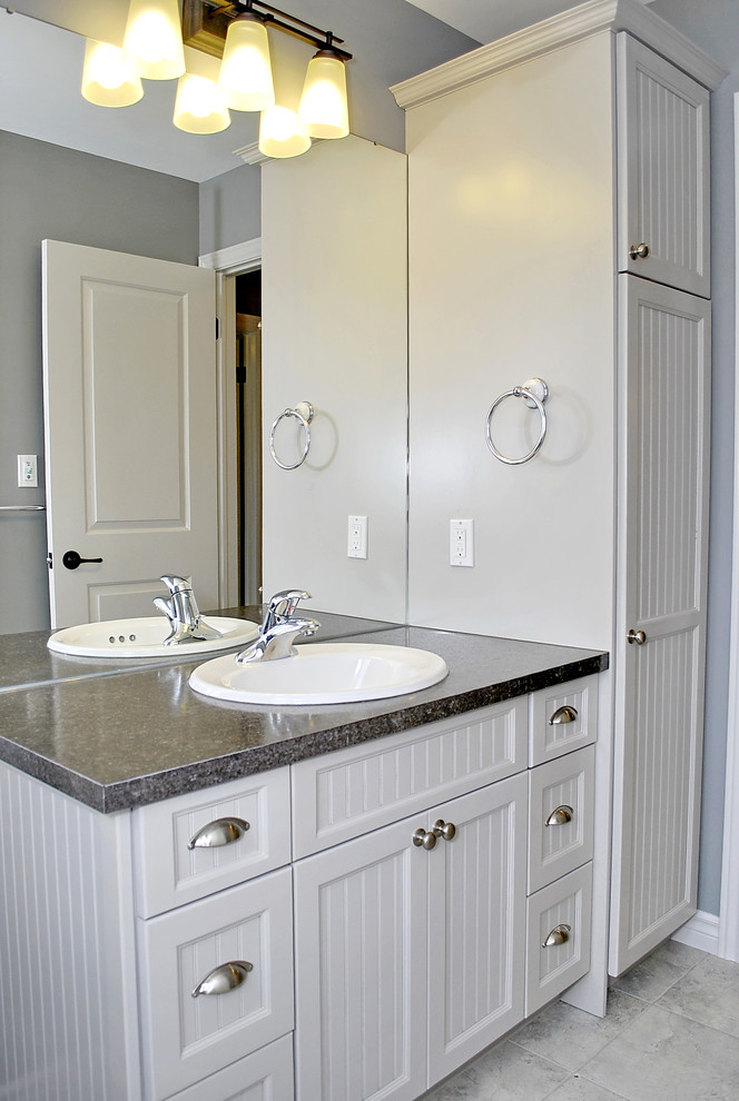 На фото: ванная комната среднего размера в стиле кантри с белыми фасадами, столешницей из ламината, серыми стенами, полом из керамической плитки и фасадами с утопленной филенкой