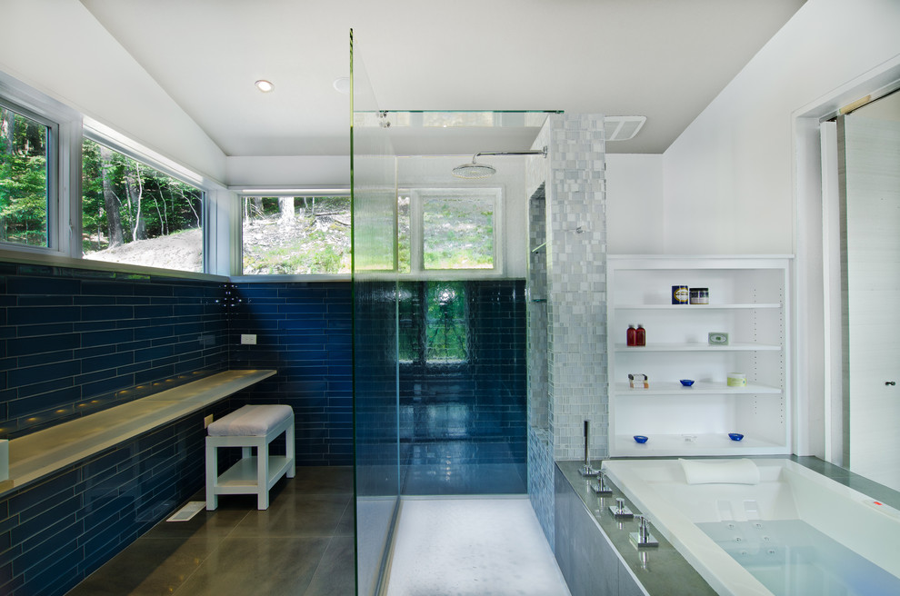 ワシントンD.C.にある中くらいなコンテンポラリースタイルのおしゃれなマスターバスルーム (白いキャビネット、ガラスの洗面台、ドロップイン型浴槽、バリアフリー、青いタイル、コンクリートの床、青い壁) の写真