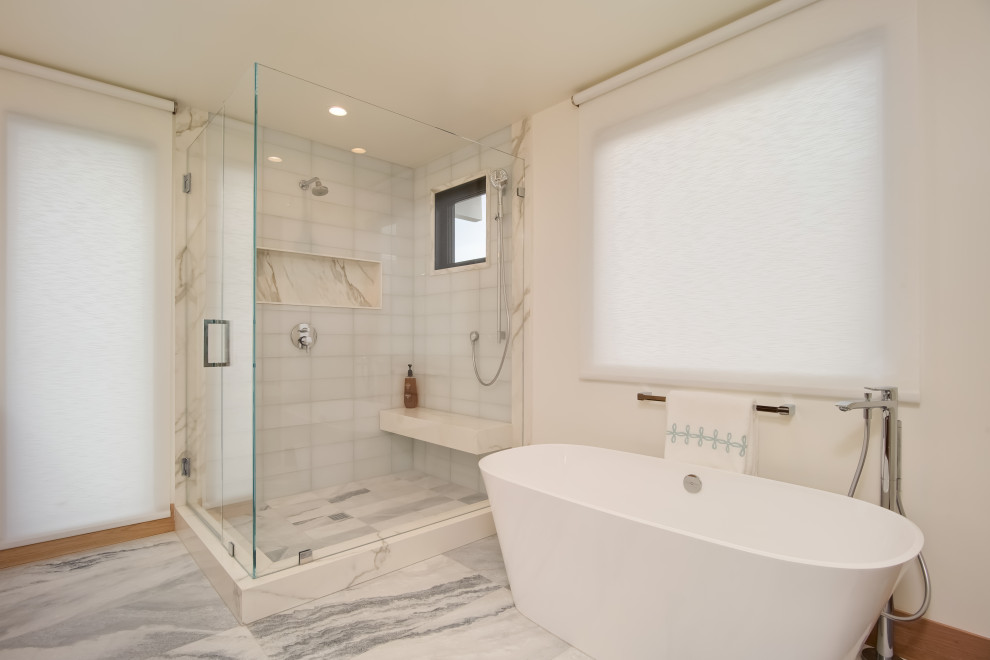 Inspiration pour une grande salle de bain principale design en bois clair avec un placard à porte affleurante, une baignoire indépendante, une douche d'angle, WC à poser, un carrelage blanc, des carreaux de porcelaine, un mur blanc, un sol en marbre, un lavabo encastré, un plan de toilette en marbre, un sol blanc, une cabine de douche à porte battante, un plan de toilette blanc, un banc de douche, meuble double vasque et meuble-lavabo suspendu.