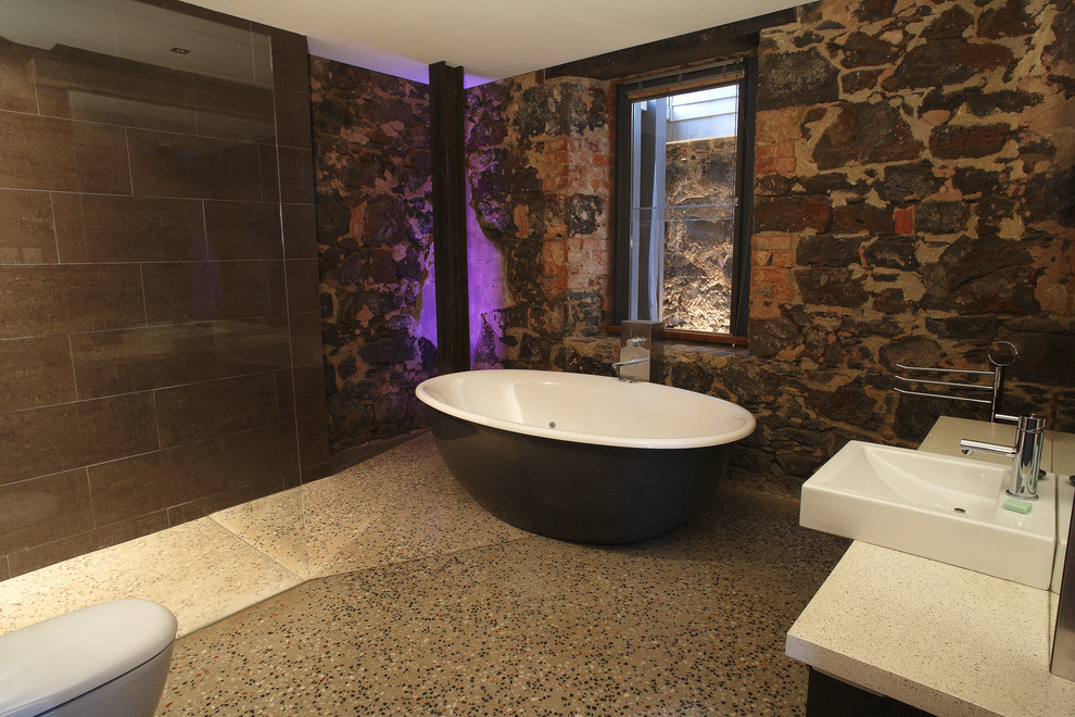 Cette image montre une salle de bain chalet avec une vasque, un plan de toilette en quartz modifié, une baignoire indépendante, une douche à l'italienne, WC à poser, un carrelage marron et des carreaux de porcelaine.
